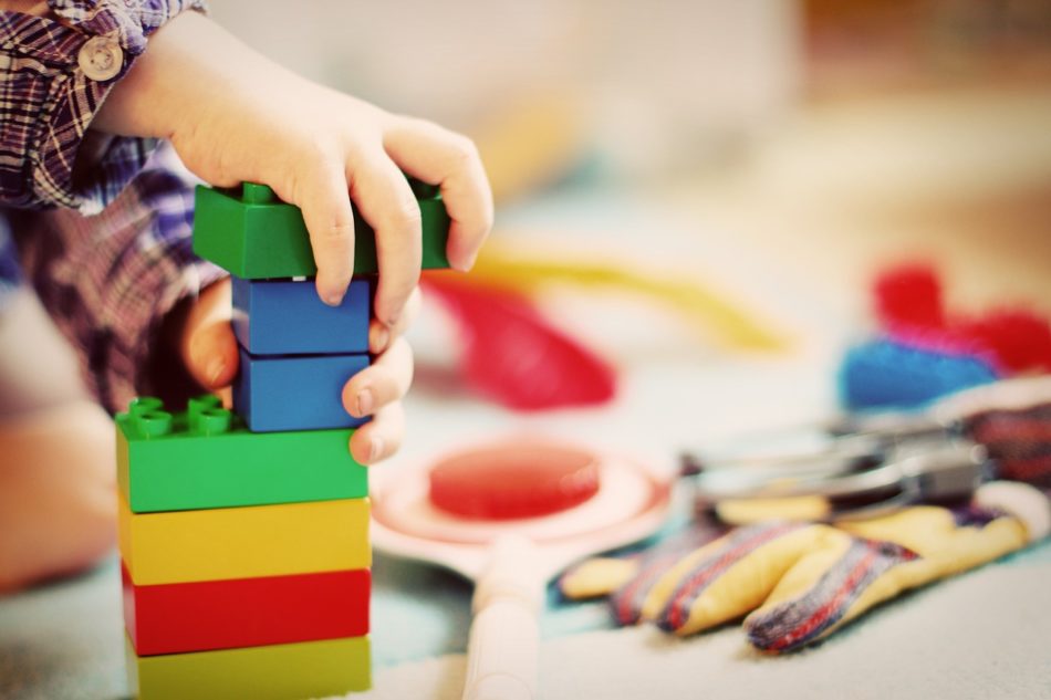 bērna rokas tuvplānā, kas spēlējas ar krāsainiem klucīšiem